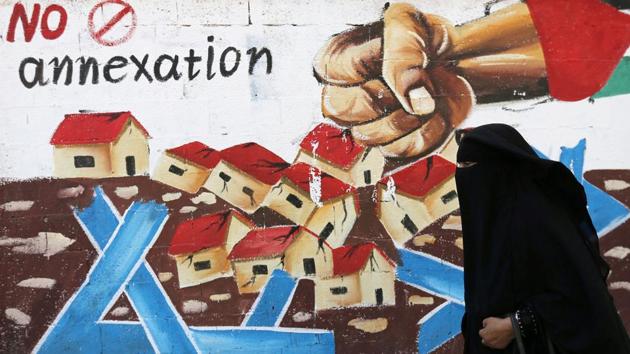 A Palestinian woman walks past a mural against Israel's plan to annex parts of the Israeli-occupied West Bank, in Rafah in the southern Gaza Strip.(REUTERS)