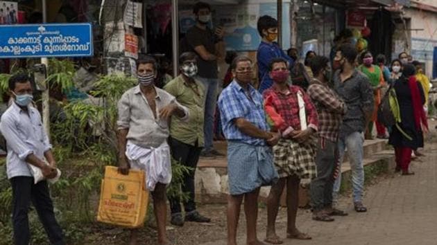 People wearing masks as a precaution against the coronavirus virus wait for transportation in Kochi, Kerala.(AP)