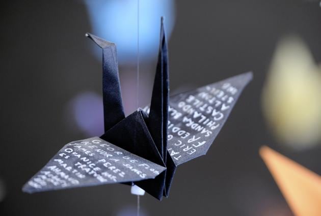 An origami paper crane with the names of victims of police violence hangs with thousands of other cranes in an exhibit for those who have died in the U.S., from COVID-19, on Tuesday, Aug. 11, 2020. Karla Funderburk started making the cranes three months earlier, stringing the paper swans in pink, blue, yellow and many other colors together and hanging them in her gallery. (AP Photo/Richard Vogel) (AP)