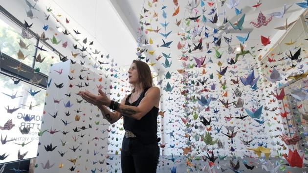 Artist Karla Funderburk, owner of Matter Studio Gallery, talks about the thousands of origami paper cranes hanging in an exhibit honouring the victims of Covid-19, in Los Angeles, Tuesday, Aug. 11, 2020. Funderburk started making the cranes three months earlier, stringing the paper swans in pink, blue, yellow and other colours together and hanging them in her gallery. (AP Photo/Richard Vogel)