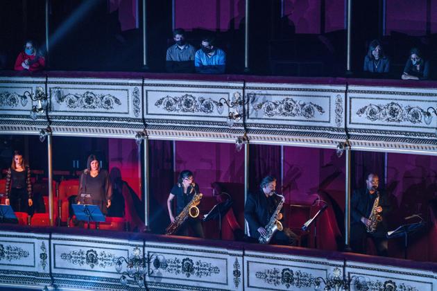 People wearing face masks amid the new coronavirus pandemic listen as musicians of the Montevideo Symphonic Band perform below them at the Solis theatre in Montevideo, Uruguay, Thursday, Aug. 13, 2020. Five months after all the live arts shows were canceled due to the pandemic, the Solis theatre reopened today for a public performance. (AP Photo/Matilde Campodonico) (AP)