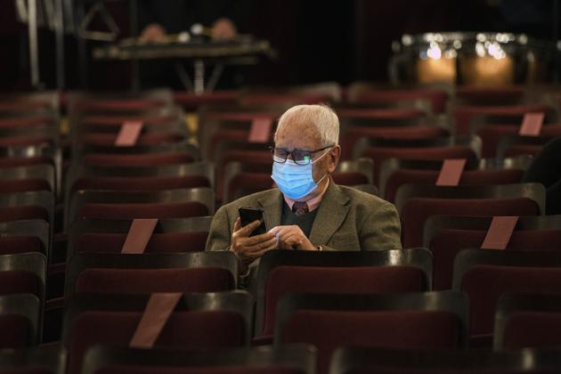 A man wearing a face a mask amid the new coronavirus pandemic waits for the start of a concert by the Montevideo Symphonic Band at the Solis theatre in Montevideo, Uruguay, Thursday, Aug. 13, 2020. Five months after all the live arts shows were canceled due to the pandemic, the Solis theatre reopened today for a public performance. (AP Photo/Matilde Campodonico) (AP)