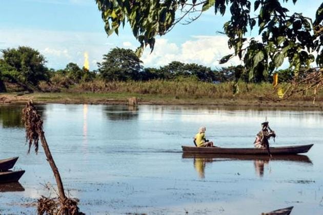 Villagers travel on a boat in the polluted Maguri Motapung?wetland as even as flames come out from an oil well run by state-owned Oil India Limited (OIL) at Baghjan?in Tinsukia district of Assam on August 6.(AFP)