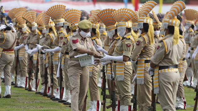 A police personnel distributes face masks to her colleagues before the start of an Independence Day parade in Jammu on August 15. Attendees at celebrations across the country wore masks and invitees, where present were seated at a distance, displaying an image of the ‘new normal’ amid Covid-19. (Channi Anand / AP) 