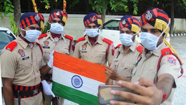 Punjab Police personnel take a selfie while holding the national flag after the parade at Polo Ground in Patiala on August 15. In view of the pandemic, the ‘at home’ programme at the Punjab and Haryana Raj Bhavans has been cancelled this year. (Bharat Bhushan / HT Photo) 