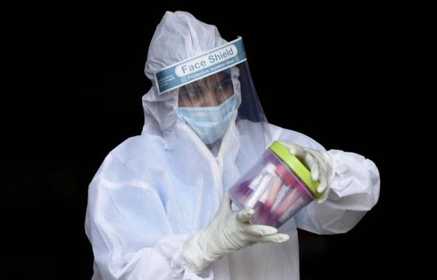 A health worker holds a container of swab samples in Gurugram.(Parveen Kumar/HT)