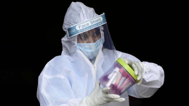 A health worker holds a container of collected swab sample in a test tube for RT-PCR coronavirus tests in Gurugram on August 14. Over 70% of those infected by the disease have recovered so far. Meanwhile, the total tests for the disease conducted in the previous 24 hours stood at a record 868,679 on August 15 according to Union Health Ministry data. (Parveen Kumar / HT Photo)
