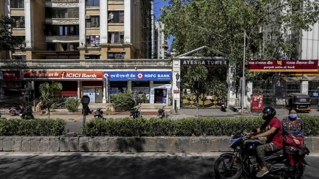 A motorcyclist and passenger travel past branches of ICICI Bank Ltd., HDFC Bank Ltd. and Punjab National Bank (PNB) on a near-empty street in Mumbai.(Bloomberg File Photo)