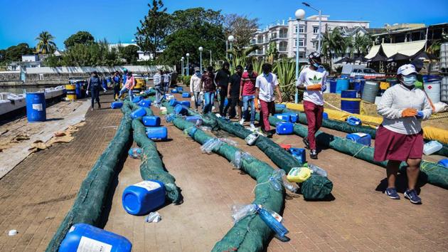 Volunteers make oil barriers to absorb leaked oil from the MV Wakashio bulk carrier on August 14. Thousands of Mauritians have volunteered day and night to clean the powder-blue waters that have long been a favourite among honeymooners and tourists. (Sumeer Mudhoo / L’Express Maurice / AFP)