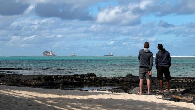Two men near Blue Bay Marine Park look at the vessel MV Wakashio on August 15. France is contributing to the relief effort with a team to help mitigate the effects of the pollution while Japan has pledged similar help. A 10-member team from India’s coast guard also arrived on the island on August 16 with 28 tonnes of equipment including booms, barges and skimmers. (Fabien Dubessay / AFP)