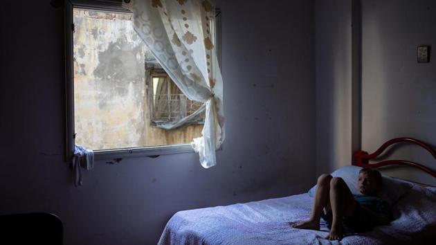 Elie Batrouni, 9, lies on a bed next to a window in his home that was damaged in the explosion, in Karantina on August 13. Batrouni’s mother found Elie, crouched down, yelling “I don’t want to die, I don’t want to die” when the explosion happened. “Now if I just clap, he gets startled and bursts into tears,” his mother said. (Alkis Konstantinidis / REUTERS) Elie Batrouni, 9, lies on a bed next to a window in his home that was damaged in the explosion, in Karantina on August 13. Batrouni’s mother found Elie, crouched down, yelling “I don’t want to die, I don’t want to die” when the explosion happened. “Now if I just clap, he gets startled and bursts into tears,” his mother said. (Alkis Konstantinidis / REUTERS)
