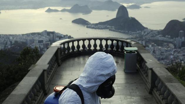 A Military member works on disinfection of the Christ the Redeemer statue, with the Sugar Loaf mountain on background ahead of its re-opening amid the coronavirus disease (COVID-19) outbreak, in Rio de Janeiro, Brazil, August 13, 2020. (REUTERS/Ricardo Moraes)