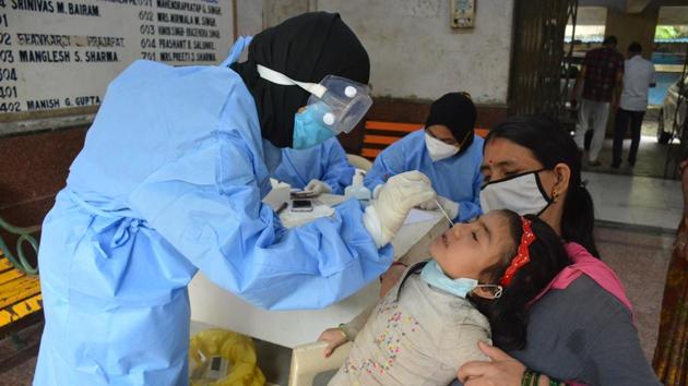 A health care worker collects the sample of a girl in Bhiwandi in Mumbai on Sunday for a test for the coronavirus disease (Covid-19). The ministry data on Monday showed there are 676,900 active Covid-19 cases and 50,921 people have succumbed to the viral disease across the country.(Praful Gangurde/ HT Photo)