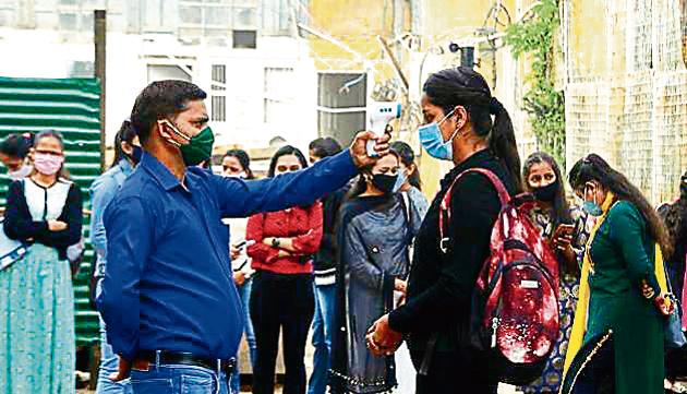 A staff member checking the body temperature of a student at RKMV College, Shimla, on Monday.(Deepak Sansta / HT)
