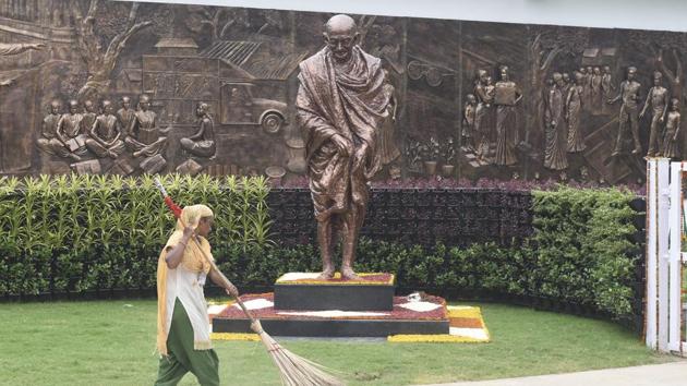 A worker sweeps an area near a statue of Mahatma Gandhi inside the Rashtriya Swachhata Kendra, an interactive experience centre on the Swachh Bharat Mission, at Rajghat in New Delhi.(PTI)