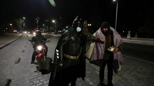 A Chilean trader and so-called 'Batman solidario' (Solidarity Batman) greets a homeless man with an elbow bump while delivering charity food rations in the street. (REUTERS)