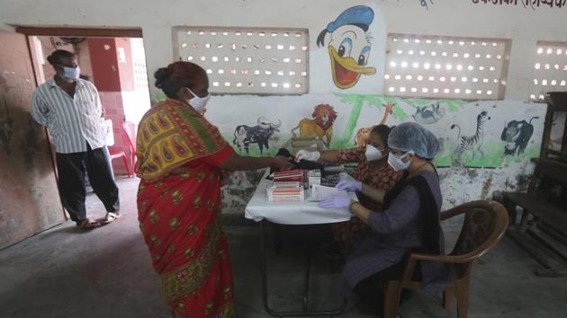 A community health worker gives medicines after screening a woman for Covid-19 and malaria symptoms at Dharavi in Mumbai on August 19. According to HT’s report, Maharashtra had reported its first case on March 9 and it took 162 days for the infections to cross the 600,000 mark. (Rafiq Maqbool / AP)