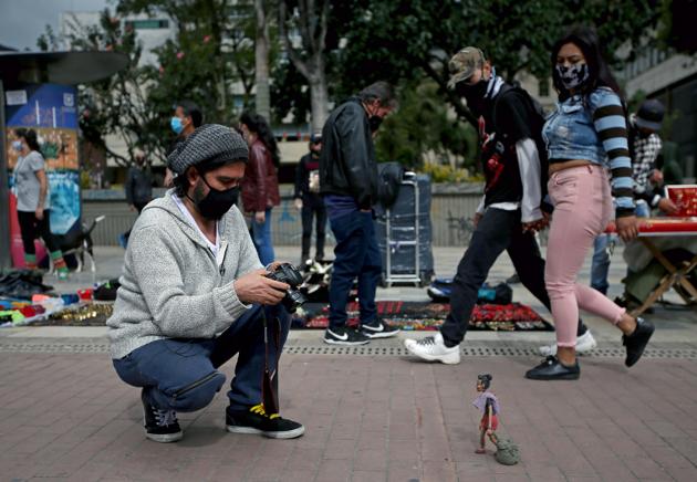 Alvarez wears a face mask as he takes pictures of his clay figure of a Venezuelan migrant, which he put on a sidewalk to photograph, amidst an outbreak of the coronavirus disease (COVID-19), in Bogota, Colombia August 7, 2020. (REUTERS) Alvarez wears a face mask as he takes pictures of his clay figure of a Venezuelan migrant, which he put on a sidewalk to photograph, amidst an outbreak of the coronavirus disease (COVID-19), in Bogota, Colombia August 7, 2020. (REUTERS)