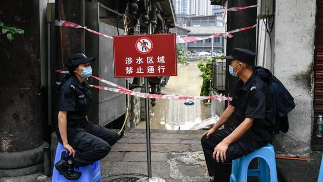 Security officials keep watch by a blocked-off alley due to floods in China's southwestern Chongqing on August 19. Floods in mountainous southwest China have washed away roads and forced tens of thousands from their homes, with authorities warning on August 19 the giant Three Gorges Dam was facing the largest flood peak in its history. (AFP)