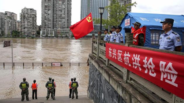 Police officers stand guard along the swollen Tuojiang River following heavy rain in Neijiang region of Sichuan province on August 19. According to a PTI report, China’s Ministry of Water Resources (MWR) has a four-tier flood control emergency response system. On August 19, the body launched level II, its second highest, emergency response for flood control. (AFP)