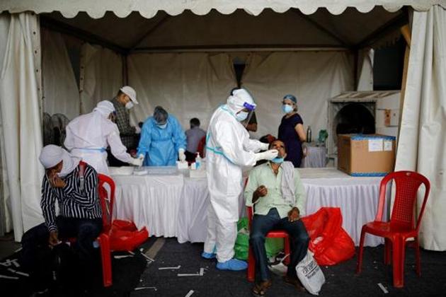 A healthcare worker wearing personal protective equipment (PPE) takes a swab from a migrant worker, who returned to Delhi from his native state, for a rapid antigen test for the coronavirus disease (Covid-19). This is the third day in a row that the daily Covid-19 cases in the country have been more than 64,000.(Reuters)