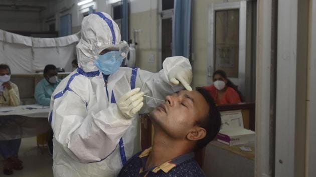 A health worker in PPE kit collects a swab sample from a man for coronavirus testing, at Sarojini Nagar in New Delhi on August 18.(Sanjeev Verma/HT Photo)