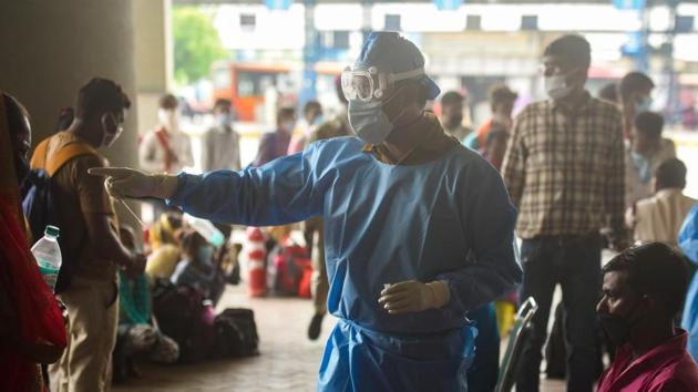 A health worker directs migrant workers arriving from other states during rapid antigen tests for Covid-19 at Anand Vihar bus terminal in New Delhi.(Amal KS/HT Photo)