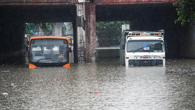 A public bus and a truck partially submerged due to severe water logging in Prahladpur, New Delhi on Wednesday.(Amal KS/HT Photo)