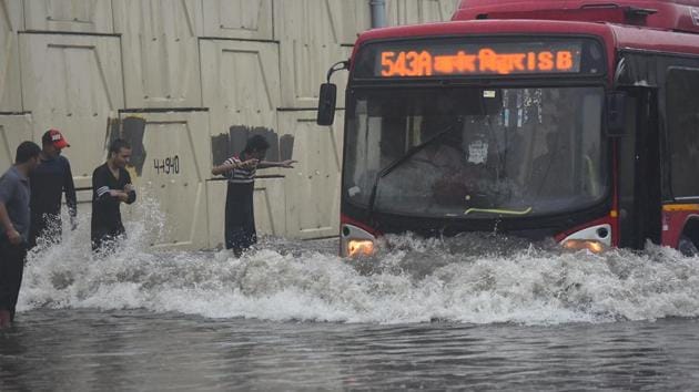 People direct a DTC bus driver to help him drive through a waterlogged stretch of road in New Delhi.(Raj K Raj/HT Photo)