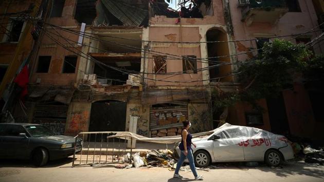 Rita Faraj Oghlo, 31, walks past a damaged building on the street that she once lived in with her husband and two children before it was damaged in an explosion on the Beirut port, in Beirut, Lebanon. (REUTERS) Rita Faraj Oghlo, 31, walks past a damaged building on the street that she once lived in with her husband and two children before it was damaged in an explosion on the Beirut port, in Beirut, Lebanon. (REUTERS)