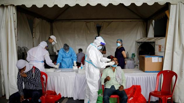 A healthcare worker wearing personal protective equipment (PPE) takes a swab from a migrant worker, who returned to Delhi from his native state, for a rapid antigen test at a bus terminal, amidst the coronavirus disease (Covid-19) outbreak in New Delhi. (REUTERS)
