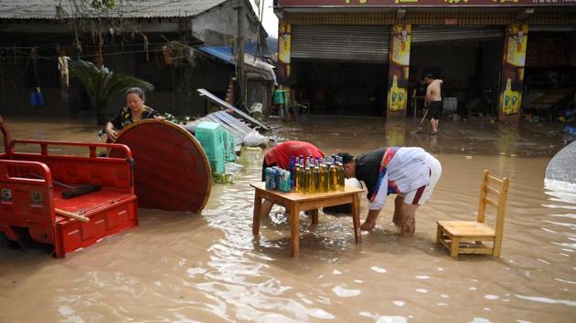 Shop owners clean up items as they stand in waters following heavy rainfall in Xiaogu Village of Sichuan province on August 19. Continuous rainfall has engulfed streets and displaced residents in the Sichuan province, with soldiers evacuating tens of thousands of people from rising floods. (Cnsphoto via REUTERS)