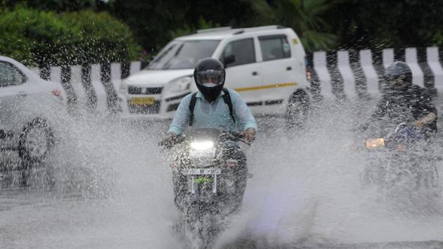 A motorcyclist passes through a heavily waterlogged stretch of road, at Sector 95, in Noida on Wednesday.(Sunil Ghosh/HT Photo)