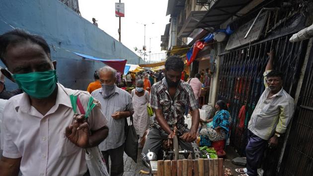 A vendor sharpens a knife while sitting on his bicycle as people wearing protective face masks move past him in a market, amidst the spread of the coronavirus disease (Covid-19) in Mumbai, India. (REUTERS) A vendor sharpens a knife while sitting on his bicycle as people wearing protective face masks move past him in a market, amidst the spread of the coronavirus disease (Covid-19) in Mumbai, India. (REUTERS)