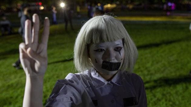 A pro-democracy student with a tape covering her mouth raises three-fingers, a symbol of resistance salute, during a protest rally at Mahidol University in Thailand on August 18. The three-finger salute has been a symbol of calls for democracy since Prime Minister Prayuth Chan-ocha first took power in a 2014 coup, Reuters reported. (Gemunu Amarasinghe / AP)