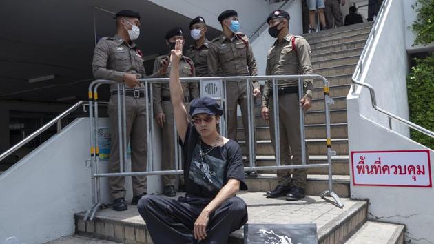 A pro-democracy activist sits in protest in front of policemen at the Samranrat police station in Bangkok on August 20. A Thai court issued arrest warrants for six more pro-democracy activists on August 19 for their involvement in recent rallies. So far, none of them have been charged with royal defamation, but their demands have angered pro-royalist supporters and spurred several smaller counterprotests, AFP reported. (Sakchai Lalit / AP)