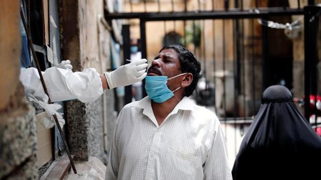 A health worker in personal protective equipment (PPE) collects a sample using a swab from a person at a local health centre to conduct tests for the coronavirus disease, in the old quarters of Delhi, on August 14.(Reuters Photo)