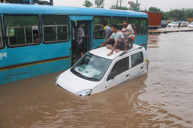 People taking refuge on a submerged car, Gurugram, August 19, 2020(PTI)