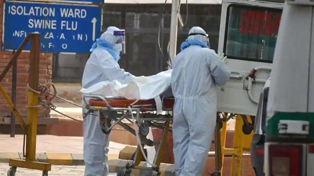 Health workers wearing protective suits shift to a van the body of a coronavirus victim, at LNJP Hospital in New Delhi.(PTI File Photo)