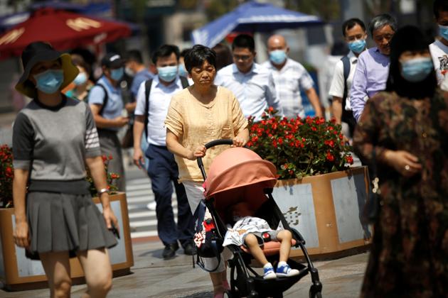 A woman without wearing a face mask pushes a baby stroller walks among people wearing face masks, after Beijing Centre for Disease Prevention and Control announced that wearing face masks are no longer mandatory outdoor in Beijing.(REUTERS) A woman without wearing a face mask pushes a baby stroller walks among people wearing face masks, after Beijing Centre for Disease Prevention and Control announced that wearing face masks are no longer mandatory outdoor in Beijing.(REUTERS)