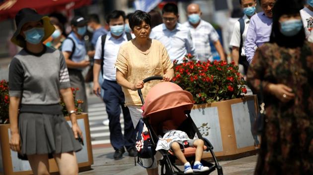 A woman not wearing a face mask pushes a baby stroller among people wearing face masks, after the Beijing Centre for Disease Prevention and Control announced that wearing face masks is no longer mandatory outdoors in Beijing, on August 21. The move brings further relaxations to rules aimed at preventing the spread the novel coronavirus after the city reported 13 consecutive days without new cases. (Tingshu Wang / REUTERS)