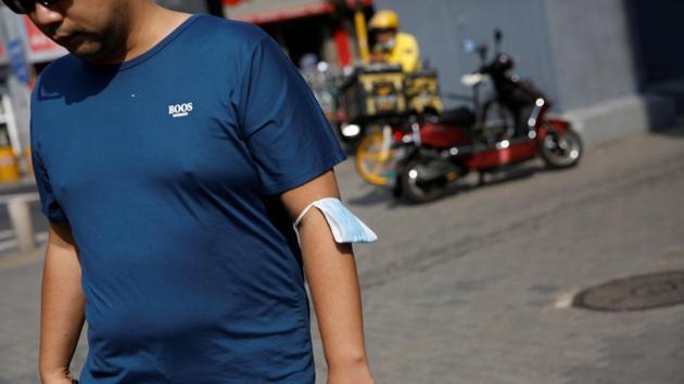 A face mask is seen on a man's arm after announcement of relaxations in Beijing on August 21. Despite the relaxed guidelines, a large proportion of people continued to wear masks in Beijing on the first day of relaxations. Some told Reuters the mask made them feel safe, while others said social pressures to wear the masks were also a factor. (Tingshu Wang / REUTERS)