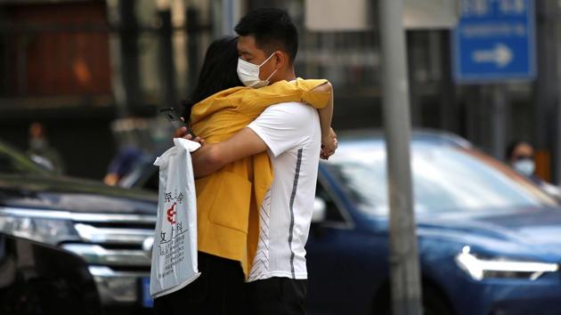 A man wearing a face mask hugs a woman on a street in Beijing on August 21. Experts say the key to the country’s success in controlling the disease has been the strict enforcement of local rules, including wearing masks, mandatory home quarantine and participating in mass testing. (Tingshu Wang / REUTERS)