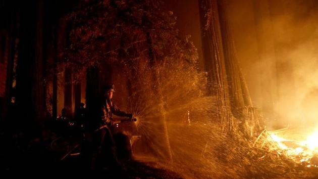 Cal Fire firefighter Anthony Quiroz douses water on a flame as he defends a home during the CZU Lightning Complex Fire in Boulder Creek, California.(REUTERS)