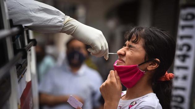 A health worker in PPE coveralls collects a swab sample from a woman to test for Covid-19 infection at Adarsh Nagar in New Delhi on Thursday.(Sanchit Khanna/HT PHOTO)