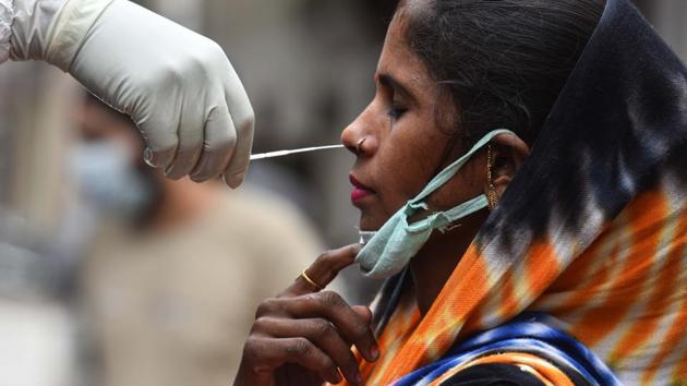 A health worker in PPE coveralls collects a swab sample from a woman to test for Covid-19 infection at Adarsh Nagar in New Delhi on Thursday.(Sanchit Khanna/HT File Photo)