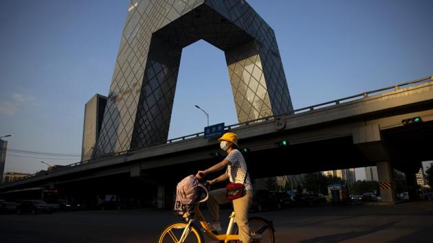 A woman waits to cross an intersection near the CCTV Building in Beijing’s central business district on August 21. It is the second time Beijing’s health authorities have relaxed guidelines on mask wearing, which has largely returned to normal after two rounds of lockdowns. The first relaxation came in late April, though rules were swiftly reversed in June after a new outbreak in a large wholesale market in the city’s south. (Mark Schiefelbein / AP)