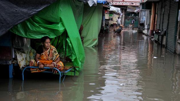 A woman sits on a cot outside her shop along a waterlogged street near Kalighat Kali temple, in Kolkata.(PTI)