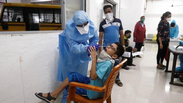 A health worker wearing personal protective equipment (PPE) takes a swab sample from a child during a check up campaign for the coronavirus disease (Covid-19), at a parking lot in Mumbai. (REUTERS) A health worker wearing personal protective equipment (PPE) takes a swab sample from a child during a check up campaign for the coronavirus disease (Covid-19), at a parking lot in Mumbai. (REUTERS)
