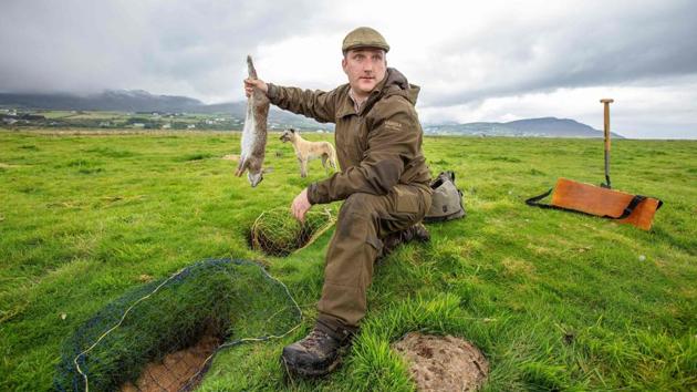 Professional rabbit catcher Steven McGonigal poses for a photograph with a caught rabbit as he hunts for them at County Donegal in northwest Ireland on August 18. McGonigal is said to be Ireland’s last traditional rabbit catcher, preferring ferrets, dogs, spades and nets instead of modern guns and poison. (Paul Faith / AFP)